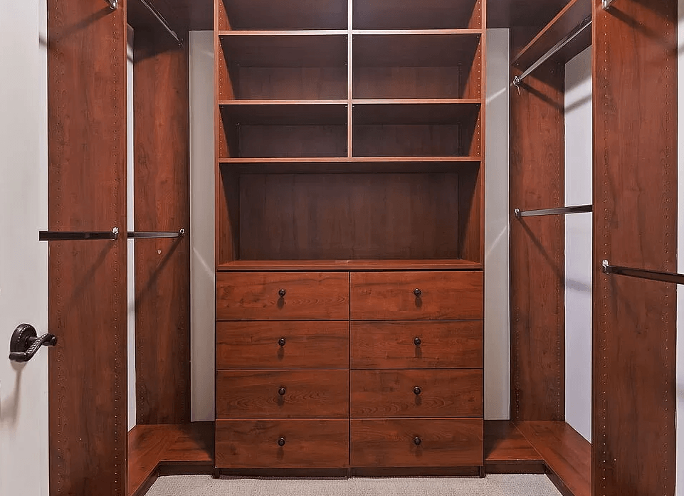 a walk in closet with wooden shelves and drawers